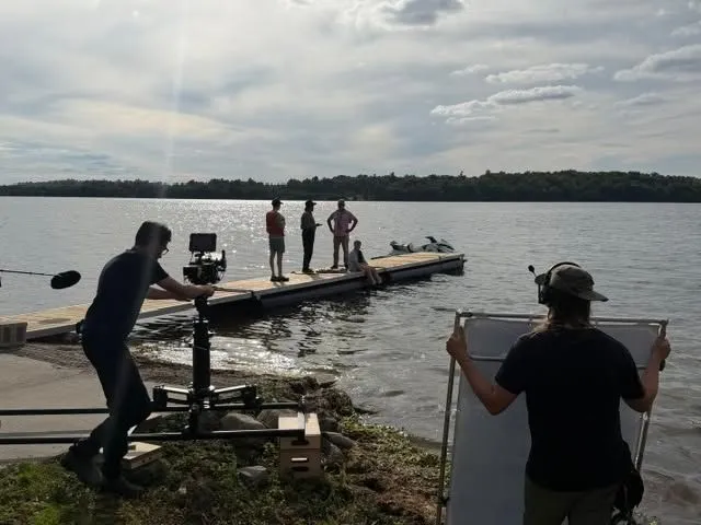 Camera crew filming a scene at a dock beside the water